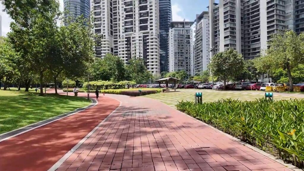 Red jogging track through KLCC Park with city towers behind