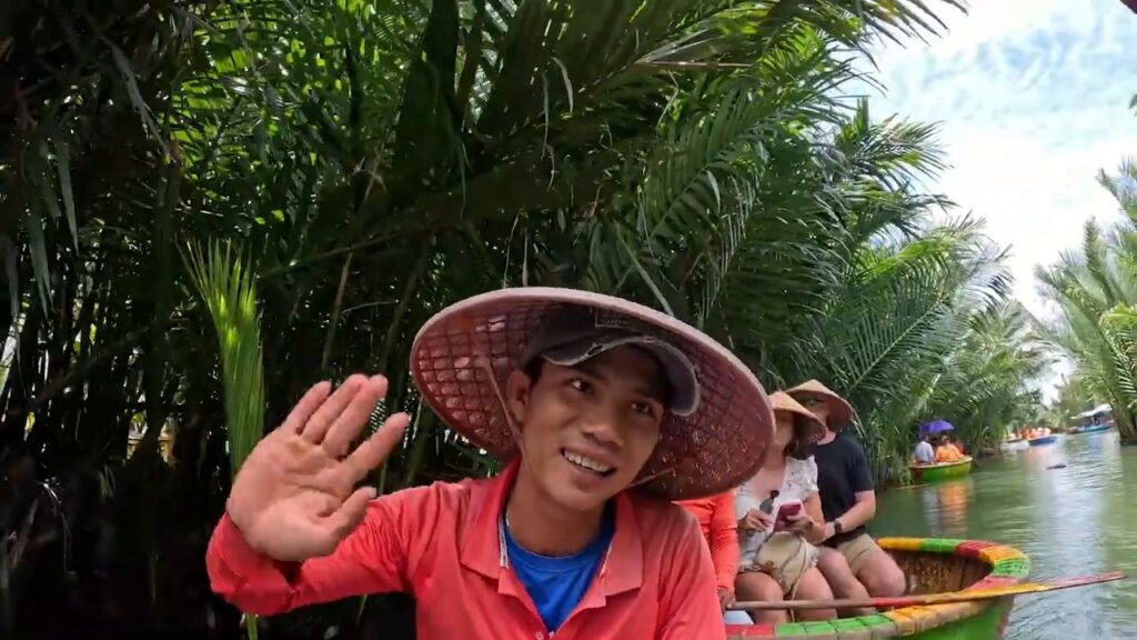Basket boat guide in a conical hat waving on the river