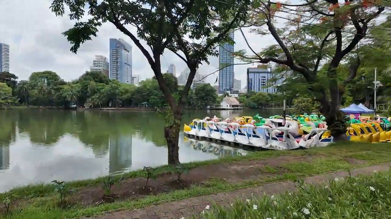 Lumphini Park lake with swan paddle boats and the Bangkok skyline