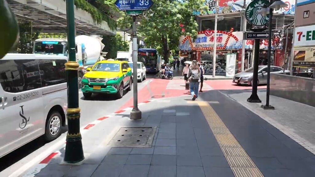 Sukhumvit Road sidewalk with taxis and shops in Bangkok