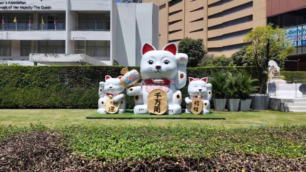 Giant lucky cat statues on a lawn along Sukhumvit Road