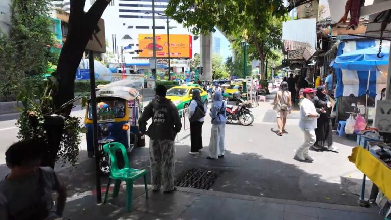 Busy Sukhumvit Road sidewalk with a tuk-tuk and vendors near Nana, Bangkok