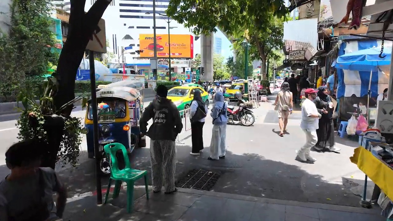 Busy Sukhumvit Road sidewalk with a tuk-tuk and vendors near Nana, Bangkok