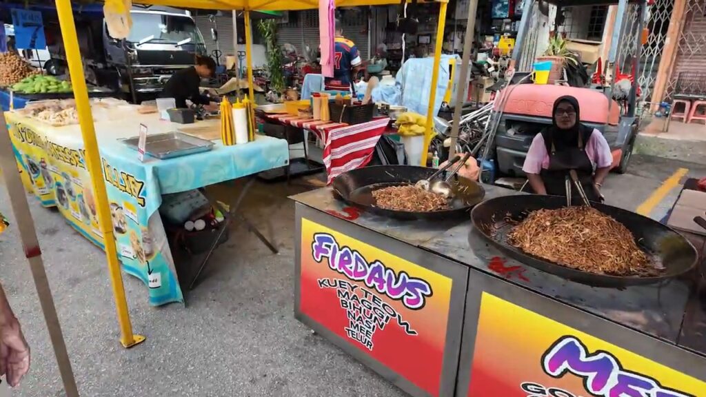 Hawker frying noodles in a giant wok at the Kepong night market