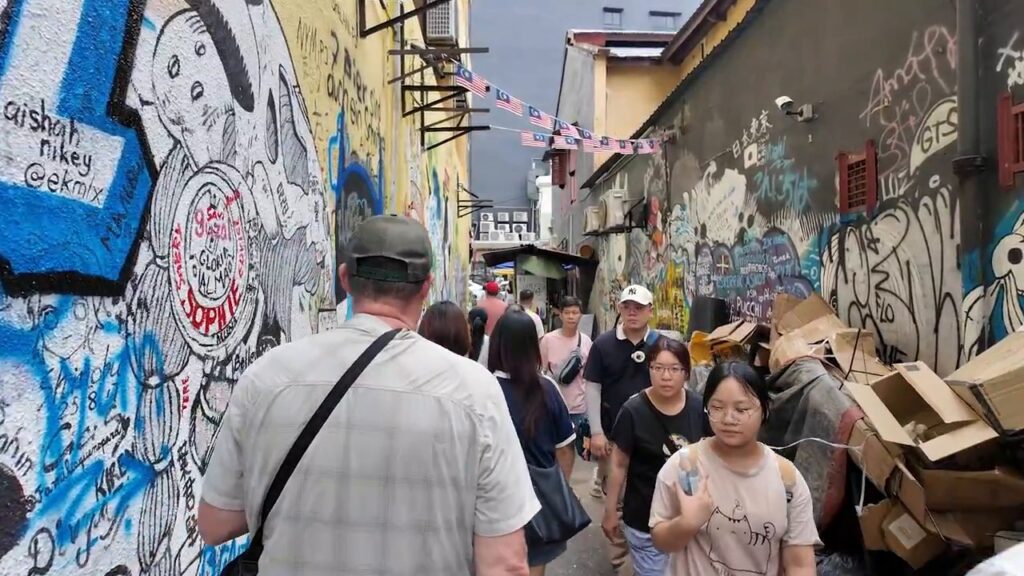 Graffiti-covered lane crowded with visitors in Kuala Lumpur Chinatown