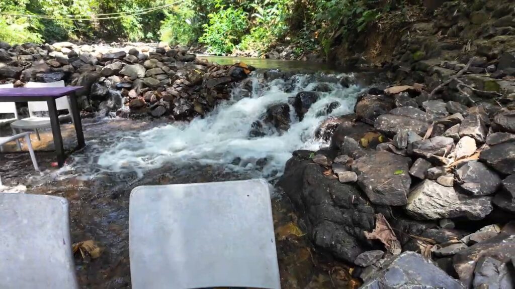 Table set in a flowing stream at a riverside BBQ lamb restaurant in Kemensah