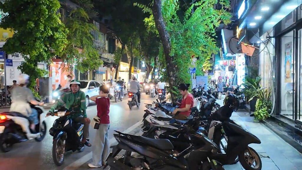 Scooters and pedestrians on a busy Old Quarter street at night