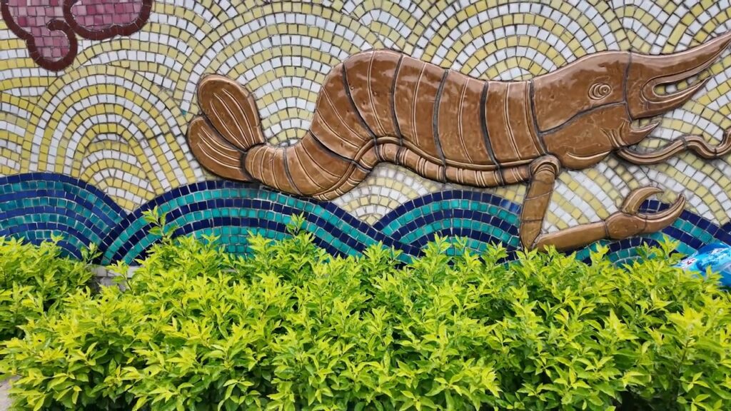 Ceramic mosaic of a shrimp over blue waves on the Hanoi mural