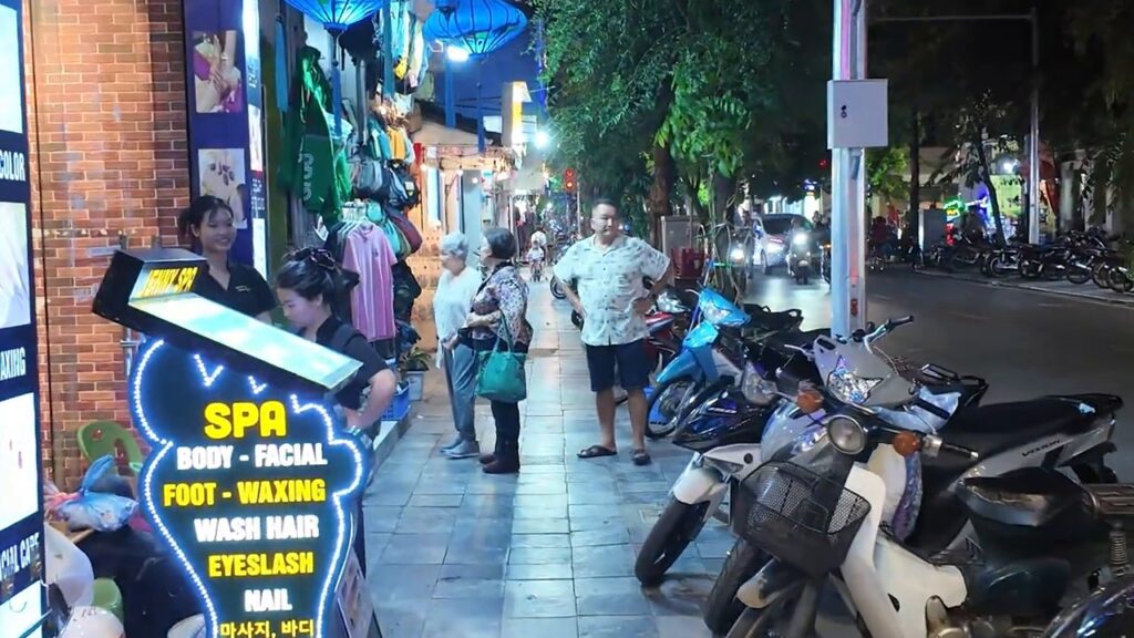 Spa sign and crowded sidewalk in the Hanoi Old Quarter at night
