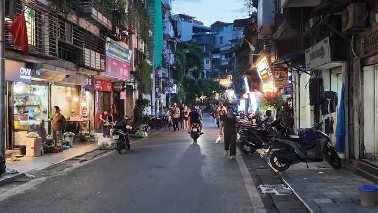 Old Quarter street at dusk in Hanoi, lined with shops and scooters