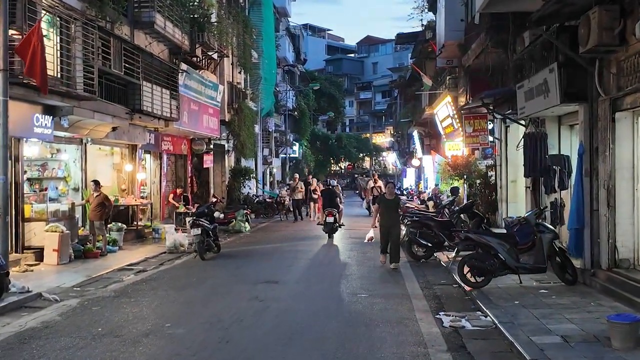 Old Quarter street at dusk in Hanoi, lined with shops and scooters